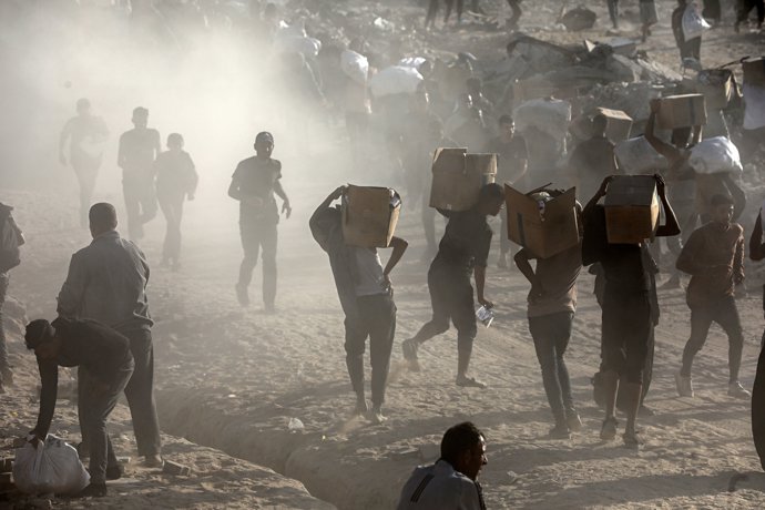 16 June 2025, Palestinian Territories, Gaza City: Palestinians carry food parcel, distributed by 'Gaza Humanitarian Relief Foundation' as people struggle with hunger amid the ongoing Israeli attacks on Gaza City.