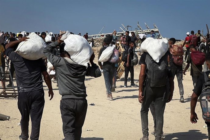Archivo - Palestinos cargan con paquetes de ayuda recibidos por la Fundaci&oacute;n Humanitaria para Gaza (GHF), en Nuseirat, en el centro de la Franja
