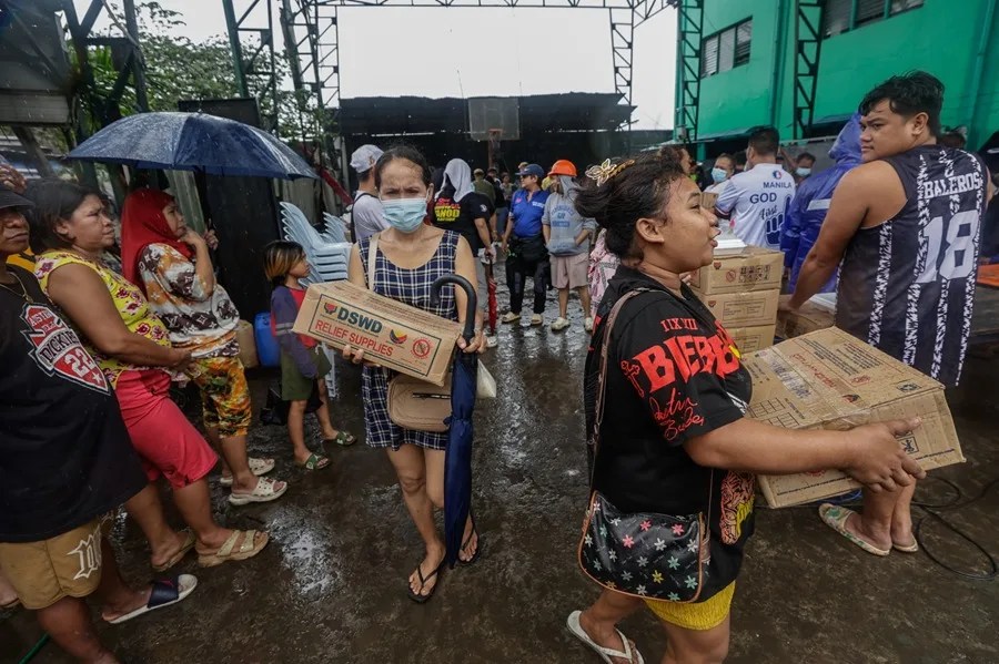 Habitantes de un distrito costero afectado por el supertif&oacute;n Fung-Wong transportan paquetes de ayuda en Manila, Filipinas.