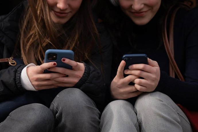 Archivo - Dos personas usan el teléfono móvil,