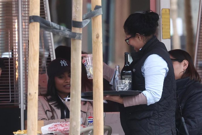 Archivo - Una camarera atiende a varios clientes en una terraza de Madrid