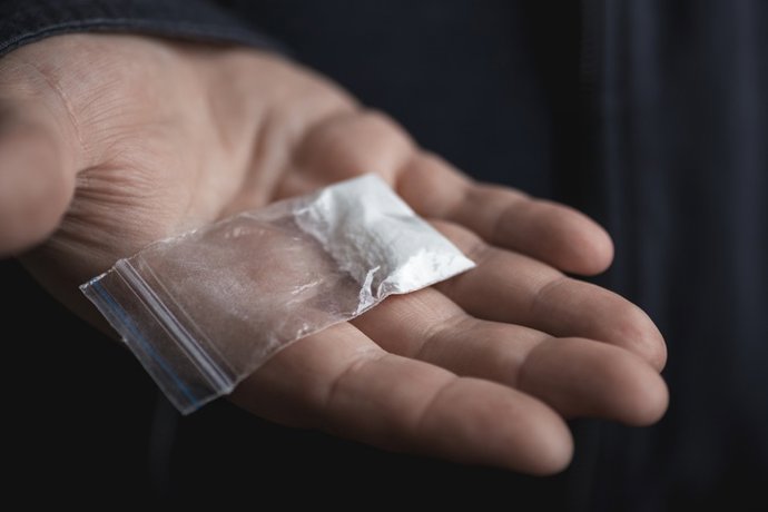 Archivo - Imagen de recurso de una mano de hombre sosteniendo un paquete de pl&aacute;stico on polvo de coca&iacute;na u otras drogas.