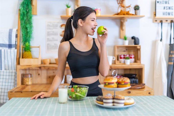 Archivo - Joven en ropa deportiva comiendo sano en lugar de elegir comida basura.